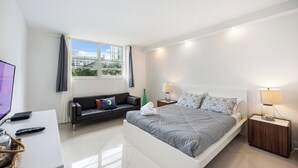 Et moderne soveværelse med seng, sofa, skrivebord og fjernsyn.