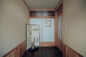 A hallway with wooden paneling, a sliding door with a decorative panel, and a small shelf with a sculpture and a bowl.