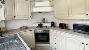 A kitchen with white cabinets, a gas stove, an oven, a microwave, and a toaster. - Unwind at Hebburn House-Your Serene Retreat Awaits (Hebburn)