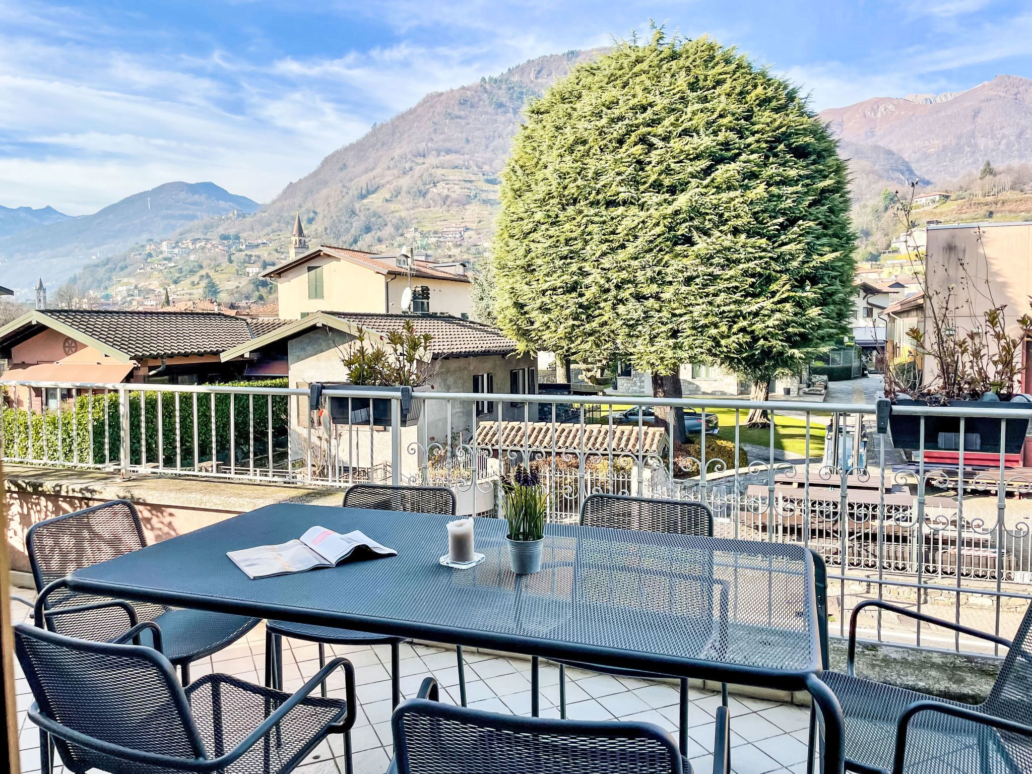 Um terraço com área de estar ao ar livre, vista para uma montanha e uma grande árvore.