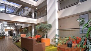 A spacious indoor area with a high ceiling, a staircase, and multiple seating areas with plants. - Christie Lodge Winter's Best. (Avon)