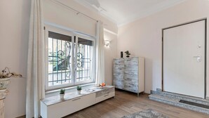 A room with a large window, a white cabinet, a door, and a patterned rug. - Blue Mermaid of Stresa, Stresa, Italy (Stresa)