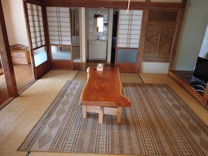 A traditional Japanese room with tatami flooring, a wooden table, a television, and sliding doors.