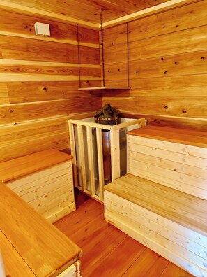 Un sauna avec des bancs en bois et un récipient en métal.