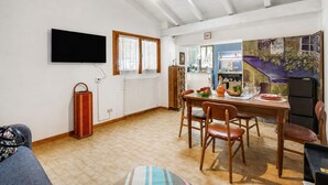 Comedor con una mesa dispuesta para cuatro, un televisor montado en la pared y un radiador en la pared.