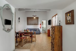 A dining area with a table, chairs, and a sofa in the background.