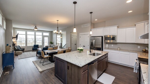 A modern kitchen with white cabinets, stainless steel appliances, and a large island.