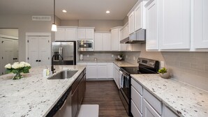 A modern kitchen with white cabinetry, stainless steel appliances, and a granite countertop.