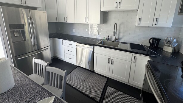 A modern kitchen with white cabinets, stainless steel appliances, and a black countertop. - Charming backyard Guesthouse with 2 bedrooms and WiFi, AC in Pleasant Hill (Pleasant Hill)
