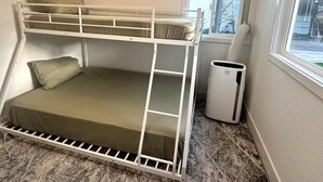 A bunk bed room with a window, a radiator, and a trash bin. - Charming backyard Guesthouse with 2 bedrooms and WiFi, AC in Pleasant Hill (Pleasant Hill)