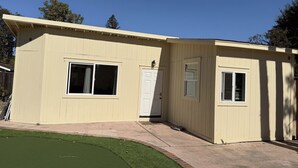 A single-story building with a beige exterior, a front door, and two windows. - Charming backyard Guesthouse with 2 bedrooms and WiFi, AC in Pleasant Hill (Pleasant Hill)