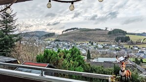 A view from a balcony with a metal railing, overlooking a town with houses and a hill in the background. - Ruhrtalblick by Interhome (Winterberg)