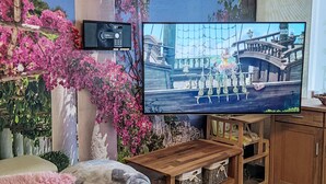 A living room with a television displaying a scenic image, a wooden cabinet, and a cozy seating area with a blanket. - Ruhrtalblick by Interhome (Winterberg)