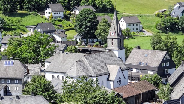 A village with traditional architecture, including a church with a tall steeple and a clock tower. - Ruhrtalblick by Interhome (Winterberg)