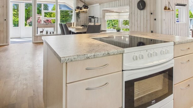 Una cocina con una isla central, horno integrado y un ventanal grande.
