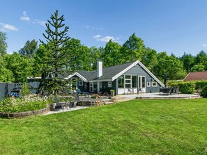 Une maison avec un patio, une pelouse et un grand arbre.