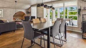 Un interior moderno con comedor, sofá y vistas a zonas verdes.