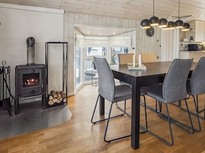 Un intérieur moderne avec un poêle à bois, une table à manger avec des chaises et un coin cuisine.