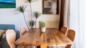 A dining area with a wooden table, wicker chairs, and a potted cactus. A framed picture of a street scene labeled "FRANCE" hangs on the wall. - Nice apartment for 3 people with WIFI and pets allowed (Ventimiglia)