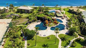 A resort with multiple swimming pools, a waterfall, and a view of the ocean.