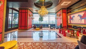 A spacious lobby with a large chandelier, red walls, and a large window offering a city view. - Arte Cheras by Minsu  (Kuala Lumpur)
