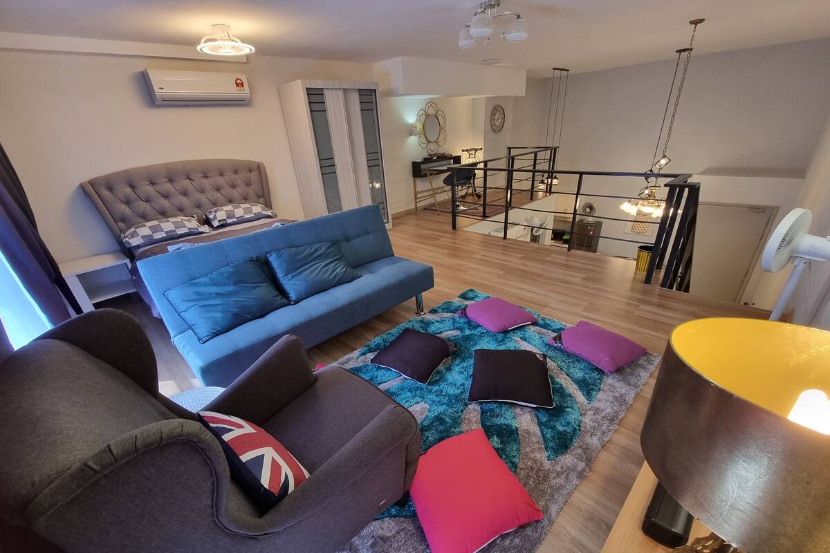 Ein modernes Wohnzimmer mit einem blauen Sofa, einem grauen Sessel und einem gemusterten Teppich.