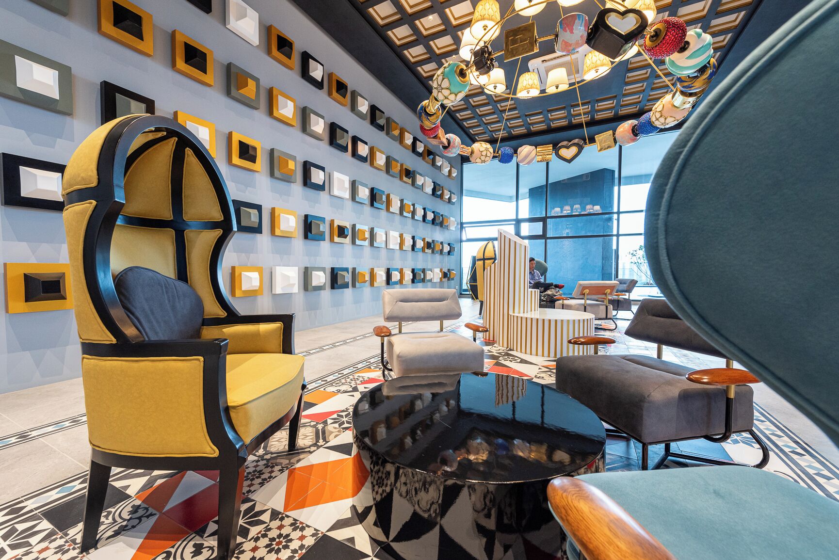 A modern interior with a geometric wall design, a variety of seating options, and a reflective coffee table.