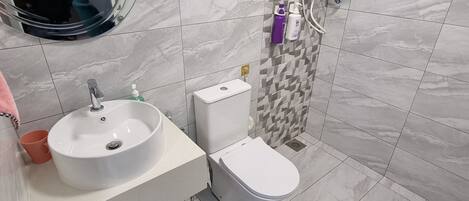 A modern bathroom with a white sink, toilet, and shower.