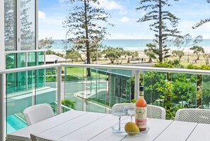 A balcony with a table, a bottle of Cosmopolitan, a glass, and a fruit. - Luxury Beachfront Stay in Kirra (Coolangatta)