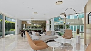 A spacious living area with a pool table, comfortable seating, and a modern kitchen in the background. - Luxury Beachfront Stay in Kirra (Coolangatta)
