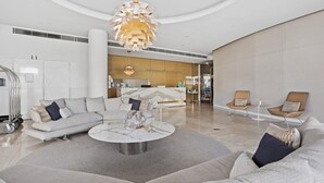 A modern living room with a sectional sofa, a round coffee table, and a unique chandelier. - Luxury Beachfront Stay in Kirra (Coolangatta)