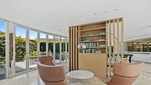A modern interior with two leather chairs, a round table, and a wooden bookshelf. - Luxury Beachfront Stay in Kirra (Coolangatta)