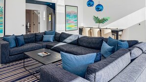 Una sala de estar moderna con un sofá seccional, una mesa de centro y un comedor con sillas.