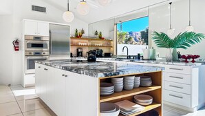 Una cocina moderna con una isla grande, electrodomésticos integrados y vistas a un paisaje montañoso.