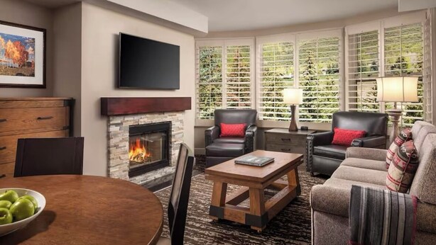A living room with a fireplace, leather chairs, a sofa, a coffee table, and a TV mounted on the wall. - VAIL Luxury 2BR Villa ~ Marriott’s Streamside (Vail)