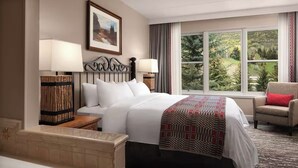 A hotel room with a large bed, two bedside lamps, a chair with a red cushion, a large window with a view of greenery, and a framed picture on the wall. - VAIL Luxury 2BR Villa ~ Marriott’s Streamside (Vail)