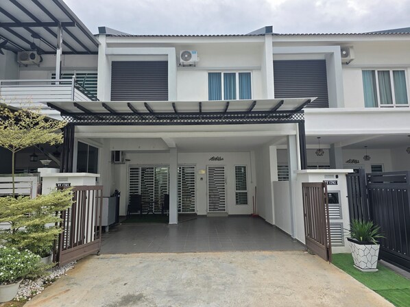 A modern two-story house with a covered entrance, air conditioning units, and a gated driveway. - Hotel O Guesthouse Dseribong (Kota Bharu)
