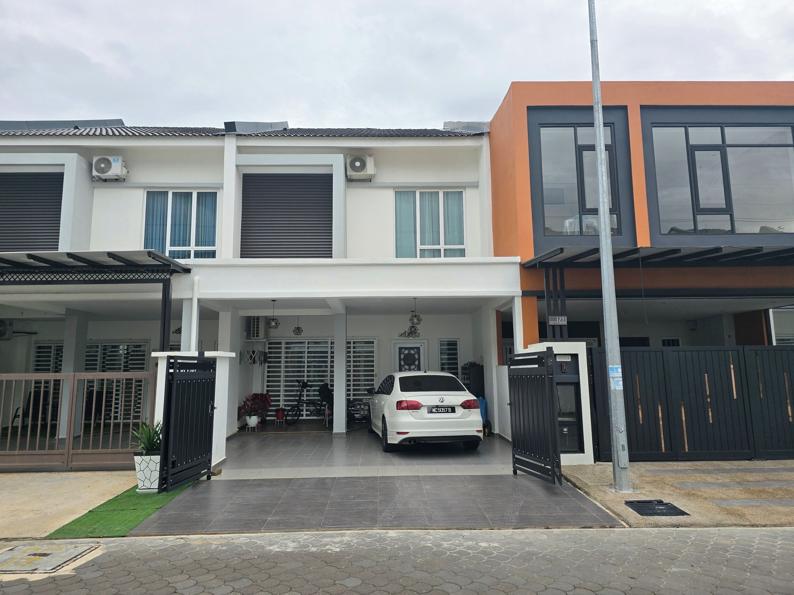 A modern two-story house with a covered driveway and a white car parked in the garage.