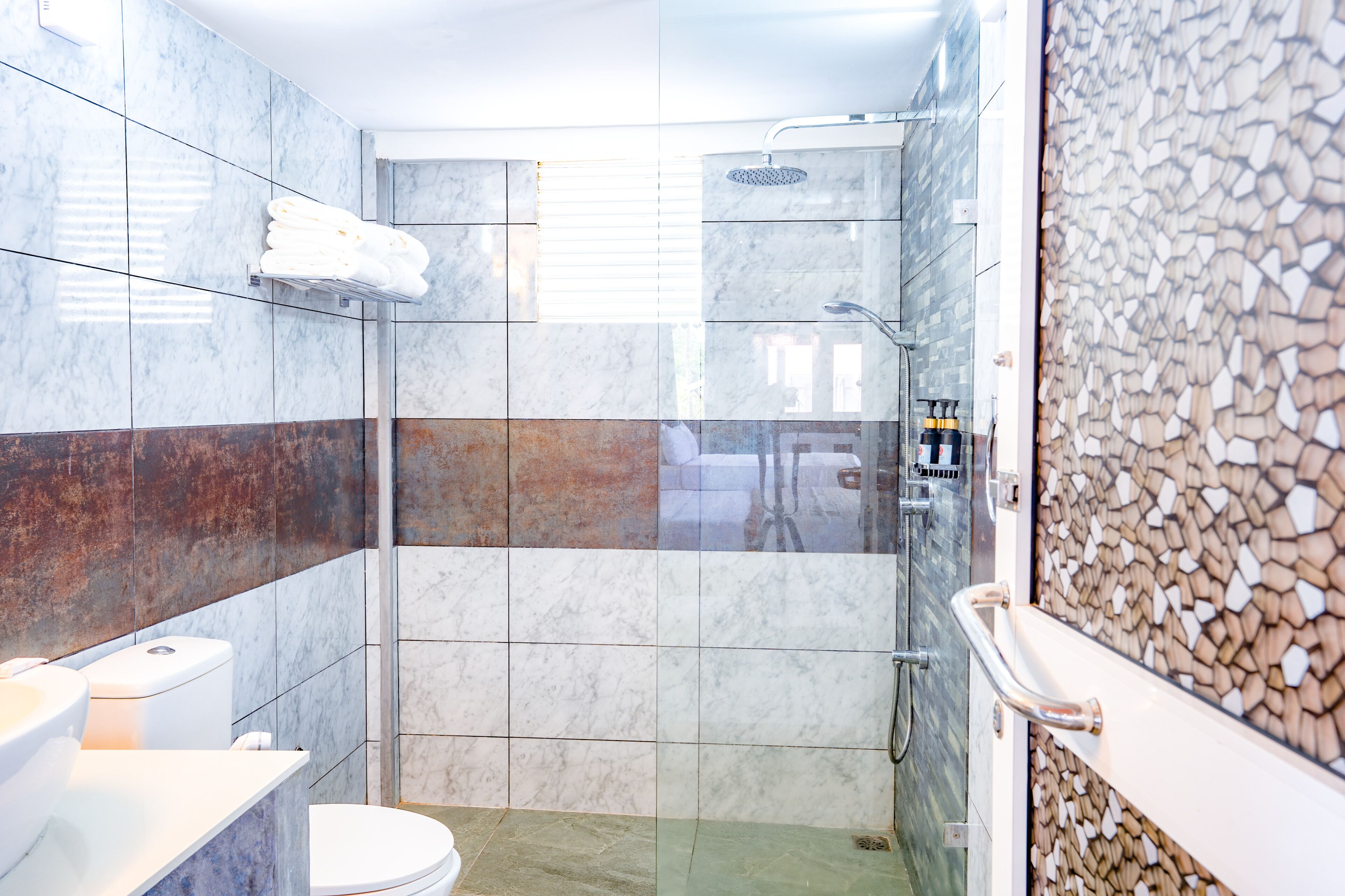 Un baño moderno con ducha de vidrio, inodoro y lavamanos.