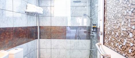 Un baño moderno con ducha de vidrio, inodoro y lavamanos.