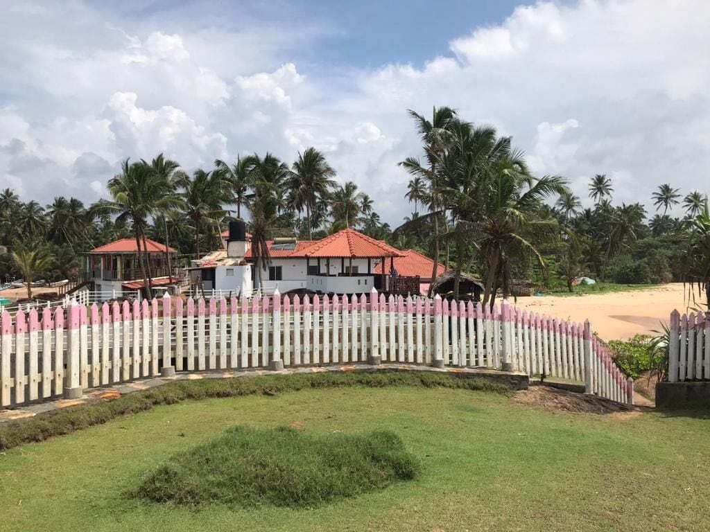 Un resort con un edificio blanco, una construcción de techo rojo y una valla de piquetes blanca.