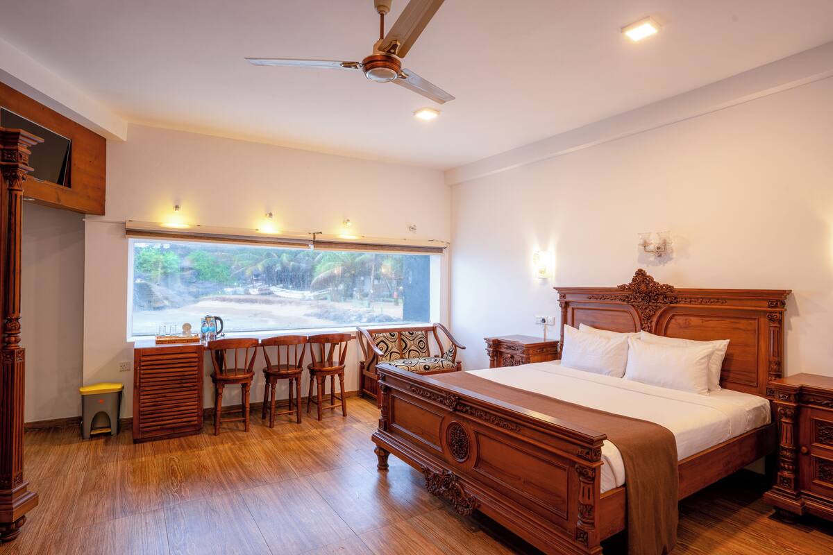 A spacious bedroom with a large bed, wooden furniture, a ceiling fan, and a view of a snowy landscape through the window.