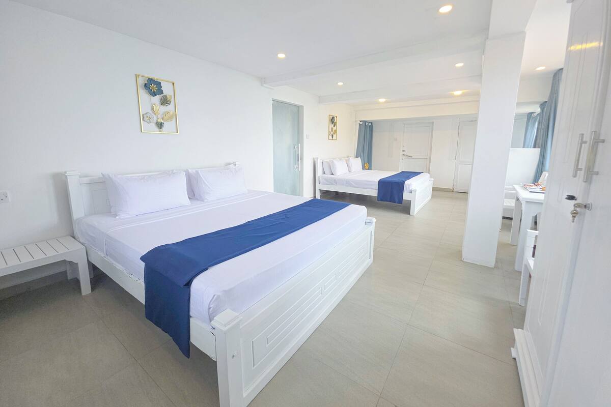 A hotel room with two beds, a desk, and a bathroom.