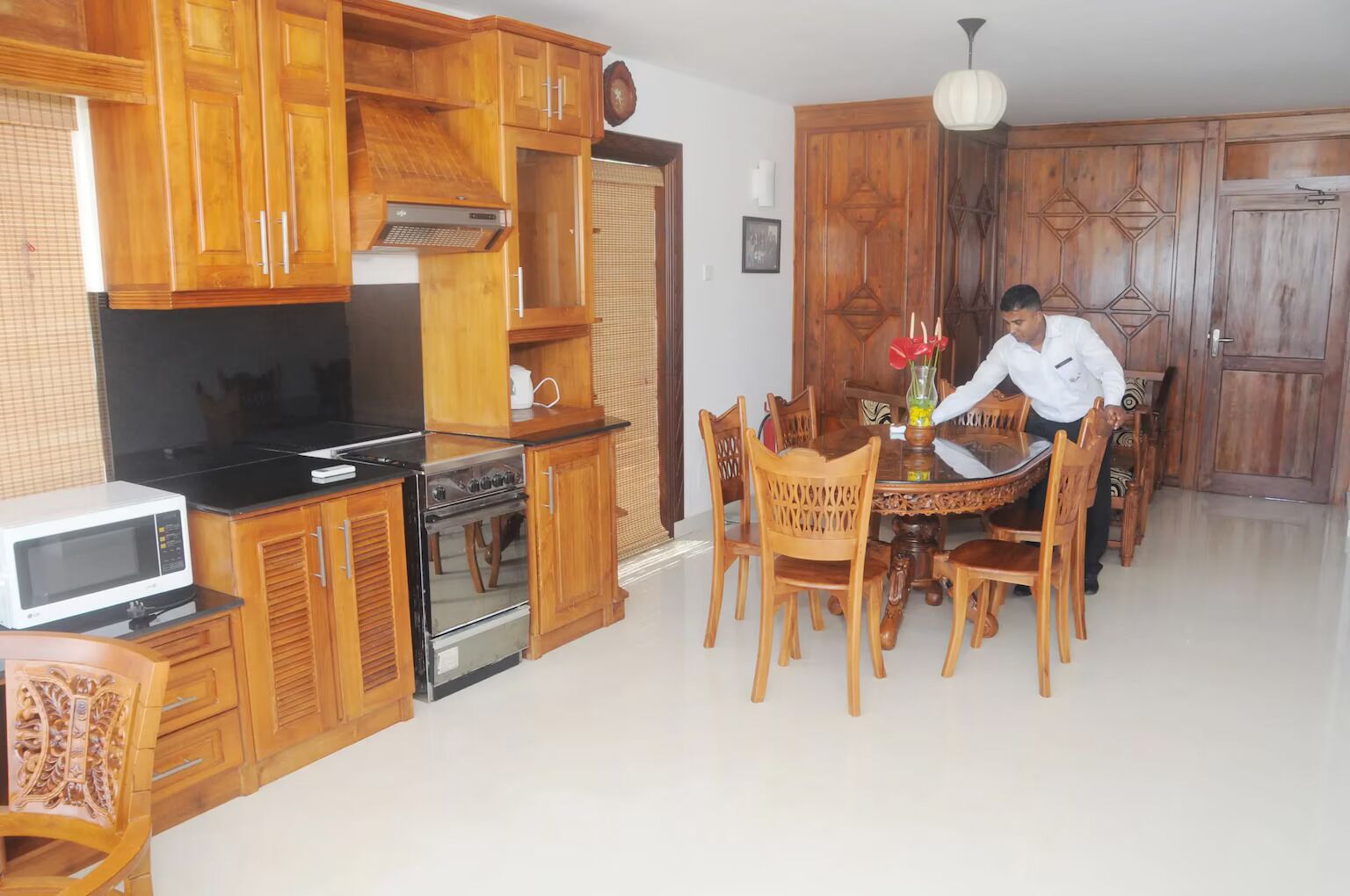 A kitchen with wooden cabinets, a microwave, stove, and a dining table with chairs.