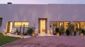 A modern building with a large entrance, potted plants, and outdoor lighting. - Villa PurSang Marrakech – Villa Privée de Luxe avec Hammam, Spa et Jardin (Marrakech)