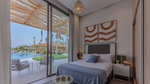 A bedroom with a large bed, a view of a swimming pool, and a patio area with chairs. - Villa PurSang Marrakech – Villa Privée de Luxe avec Hammam, Spa et Jardin (Marrakech)
