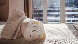 A bed with rolled towels and a view of a snowy outdoor area through a large window. - Bietschorn 20 by Interhome (Nendaz)
