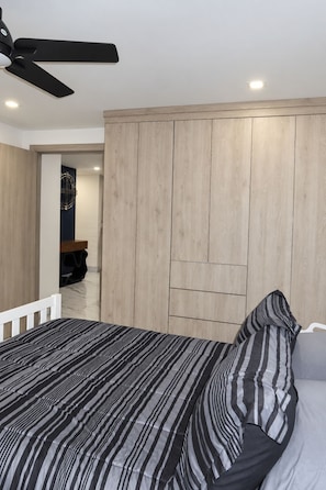 A bedroom with a bed, a ceiling fan, and a wardrobe.
