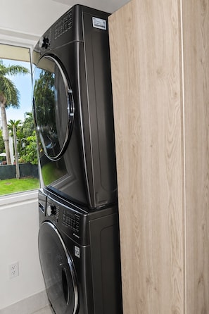 A stacked washer and dryer unit in a room with a window.
