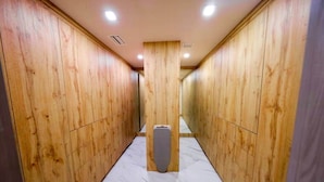 A hallway with wooden walls and a marble floor, leading to a central pillar.